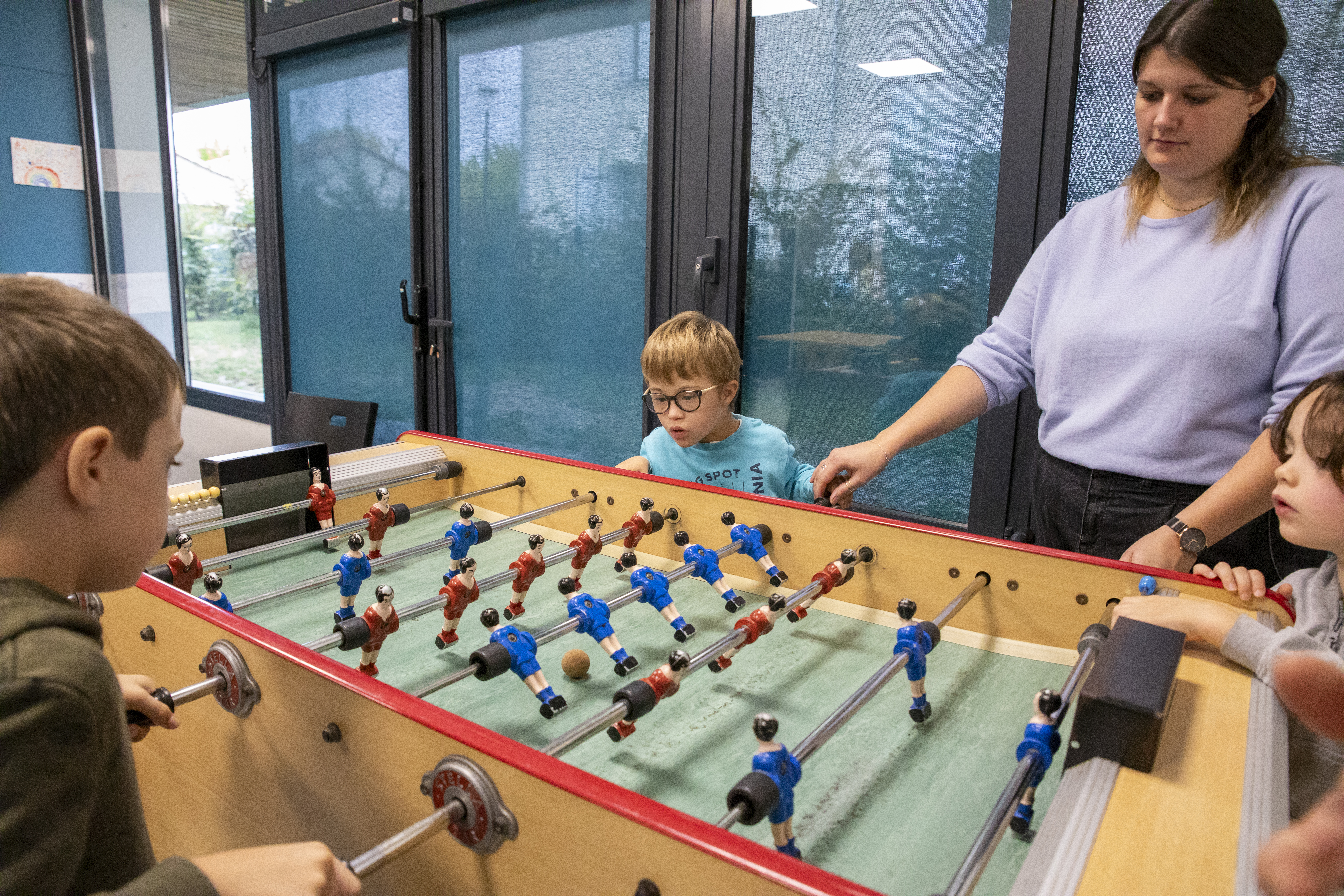 Référente et des enfants jouant au baby-foot